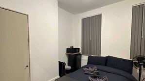 A bedroom with a bed, bedside table, and a desk with a chair. - London Vauxhall/Victoria room (Greater London)
