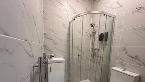 A modern bathroom with a glass-enclosed shower, a toilet, and a small sink. - London Vauxhall/Victoria room (Greater London)