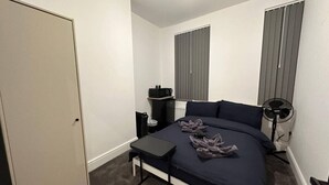 A bedroom with a bed, a desk, a chair, a radiator, and a window with blinds. - London Vauxhall/Victoria room (Greater London)