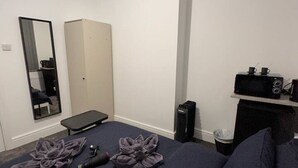 A bedroom with a bed, a wardrobe, a mirror, a bench, and a small table with a cup and a camera. - London Vauxhall/Victoria room (Greater London)