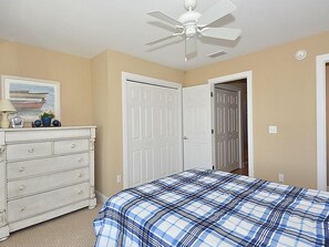 Ein Schlafzimmer mit Bett, Kommode, Deckenventilator und zwei Türen.