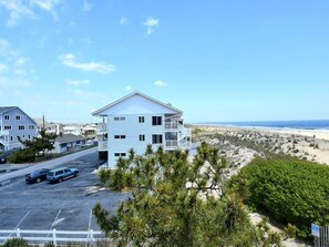 Ein Hotel direkt am Strand mit einem zweistöckigen Gebäude, einem Parkplatz und Blick auf den Strand.