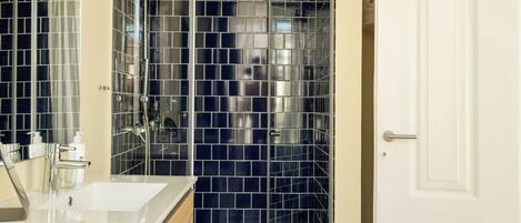 A bathroom with a black and white checkered floor, a white door, and a shower area with a glass door.