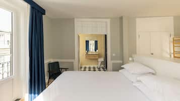 A hotel room with a bed, a chair, a bathroom with a mirror, and a view of the outside.