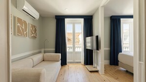 A modern room with a sofa, a TV, and a balcony view. - Esqina Apartments (Lisbon)