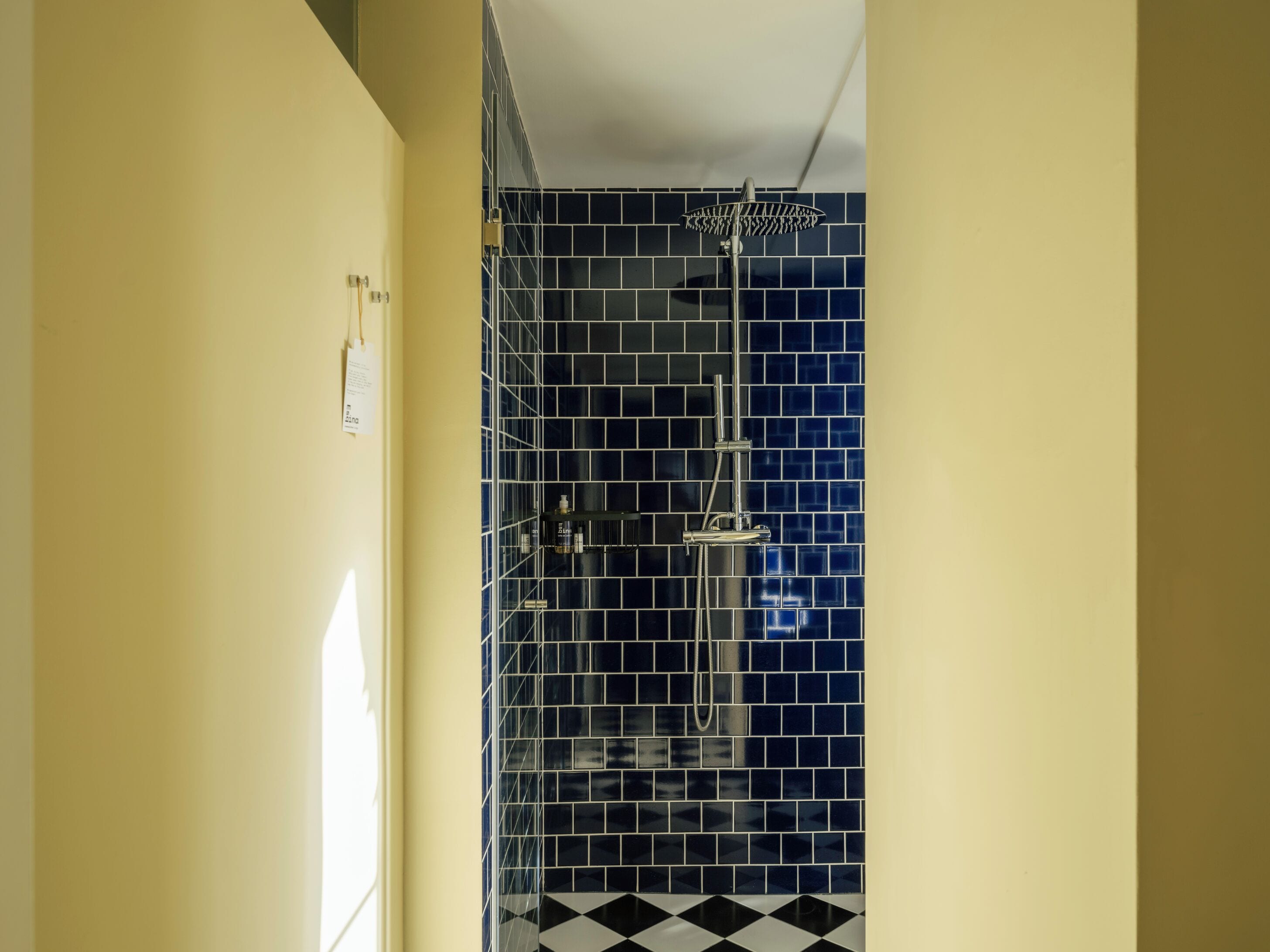 A bathroom with a shower, tiled walls, and a checkered floor.