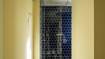 A bathroom with a shower, tiled walls, and a checkered floor.