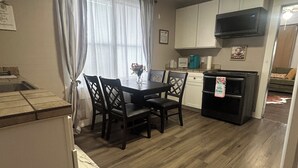 Cocina compacta con mesa, sillas, microondas y refrigerador.