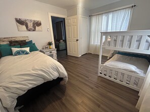 Une chambre à coucher avec un lit, un berceau, une table de chevet, une porte et un tableau au mur.