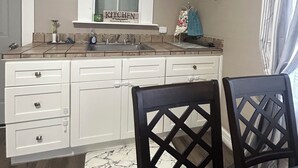 Una cocina compacta con armarios blancos, una encimera de m ármol y una ventana sobre el fregadero.