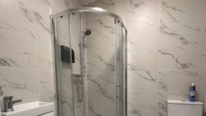 Un baño moderno con cabina de ducha de vidrio, lavamanos blanco y retrete.