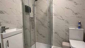 A modern bathroom with a glass-enclosed shower, a white sink, and a toilet.