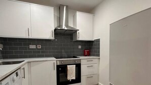 Una cocina moderna con armarios blancos, una campana de acero inoxidable, un horno empotrado y una lavadora.