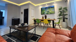 Un salon moderne comprenant un canapé, une table basse et un coin repas avec des chaises et un téléviseur.