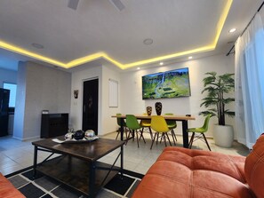 A modern living room with a sofa, a coffee table, and a dining area with chairs and a TV. - Commodity & Style Cancun (Cancún)