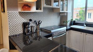 Une cuisine moderne dotée d’un plan de travail noir, d’appareils électroménagers en acier inoxydable et d’un dosseret décoré d’un motif en chevrons.