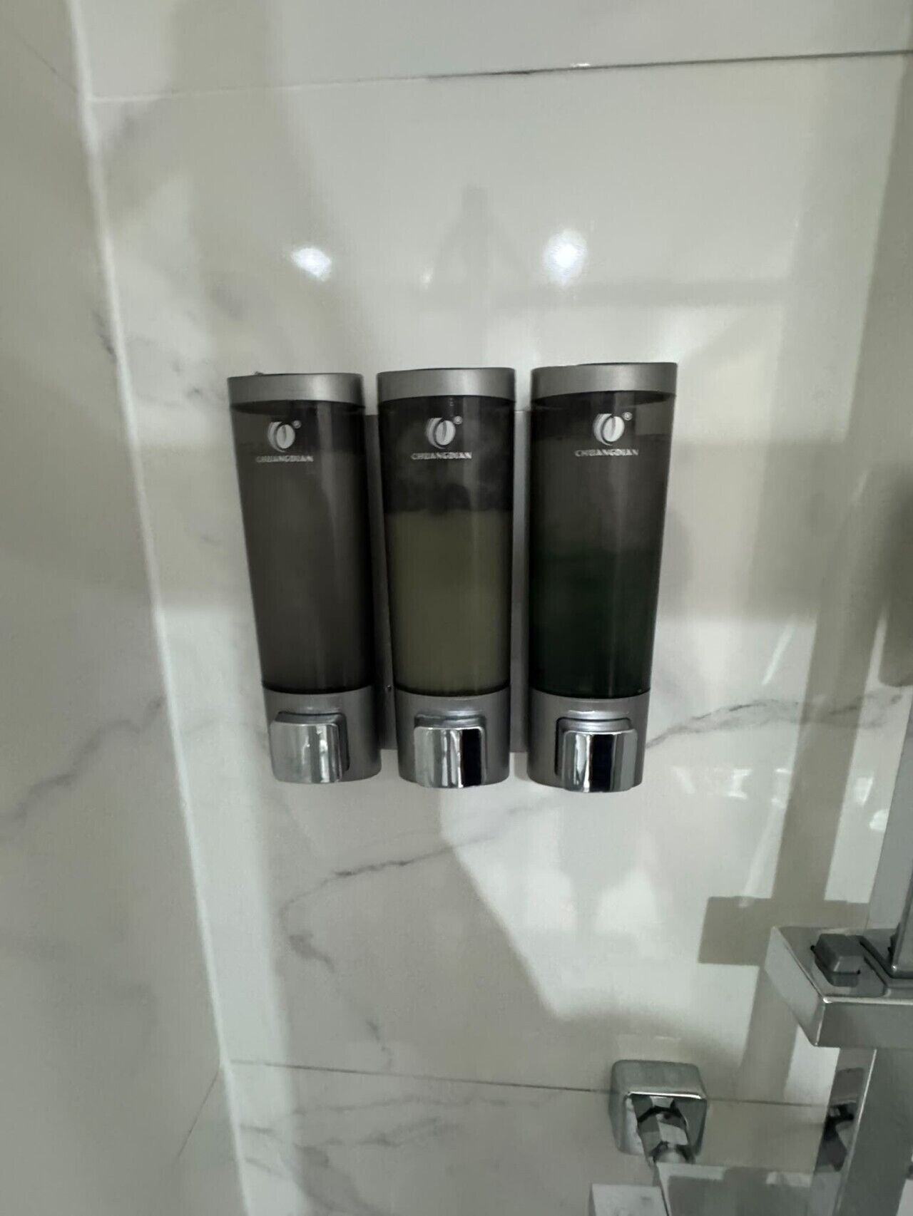 Three hand sanitizer dispensers mounted on a wall with a marble surface.