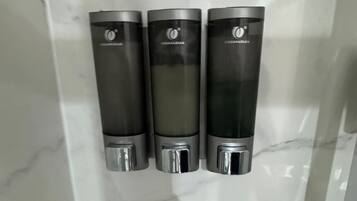 Three hand sanitizer dispensers mounted on a wall with a marble surface.