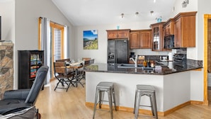 A modern kitchen with a central island, wooden cabinets, and a dining area with a table and chairs.