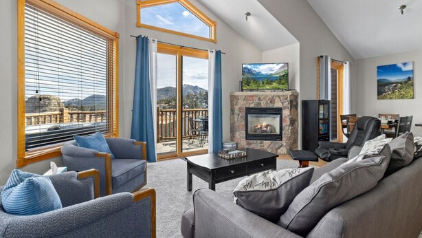 A spacious living room with a fireplace, comfortable seating, and large windows offering a scenic view.