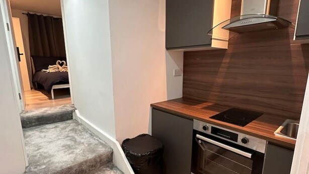 Una cocina compacta con horno integrado, una pequeña encimera y un protector de salpicaduras oscuro.