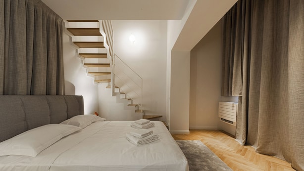 Un dormitorio con cama, una escalera y aire acondicionado instalado en la pared.