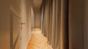 Un pasillo con suelo de madera y una fila de cortinas a un lado.