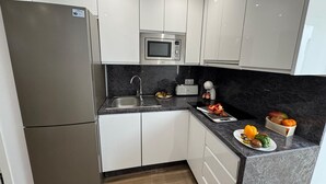 A modern kitchen with white cabinets, a stainless steel refrigerator, a microwave, and a sink. - Secunda Romana (Cordoba)