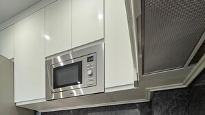 A modern kitchen with a microwave, a sink, and a cutting board with vegetables. - Secunda Romana (Cordoba)