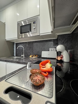A modern kitchen with a microwave, a sink, and a cutting board with vegetables. - Secunda Romana (Cordoba)