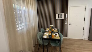 A dining area with a table set for four, a wooden floor, and a white door. - Secunda Romana (Cordoba)