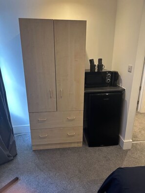 Ein kleiner Raum mit einem Holzschrank, einem schwarzen Gerät und einem Fernseher.