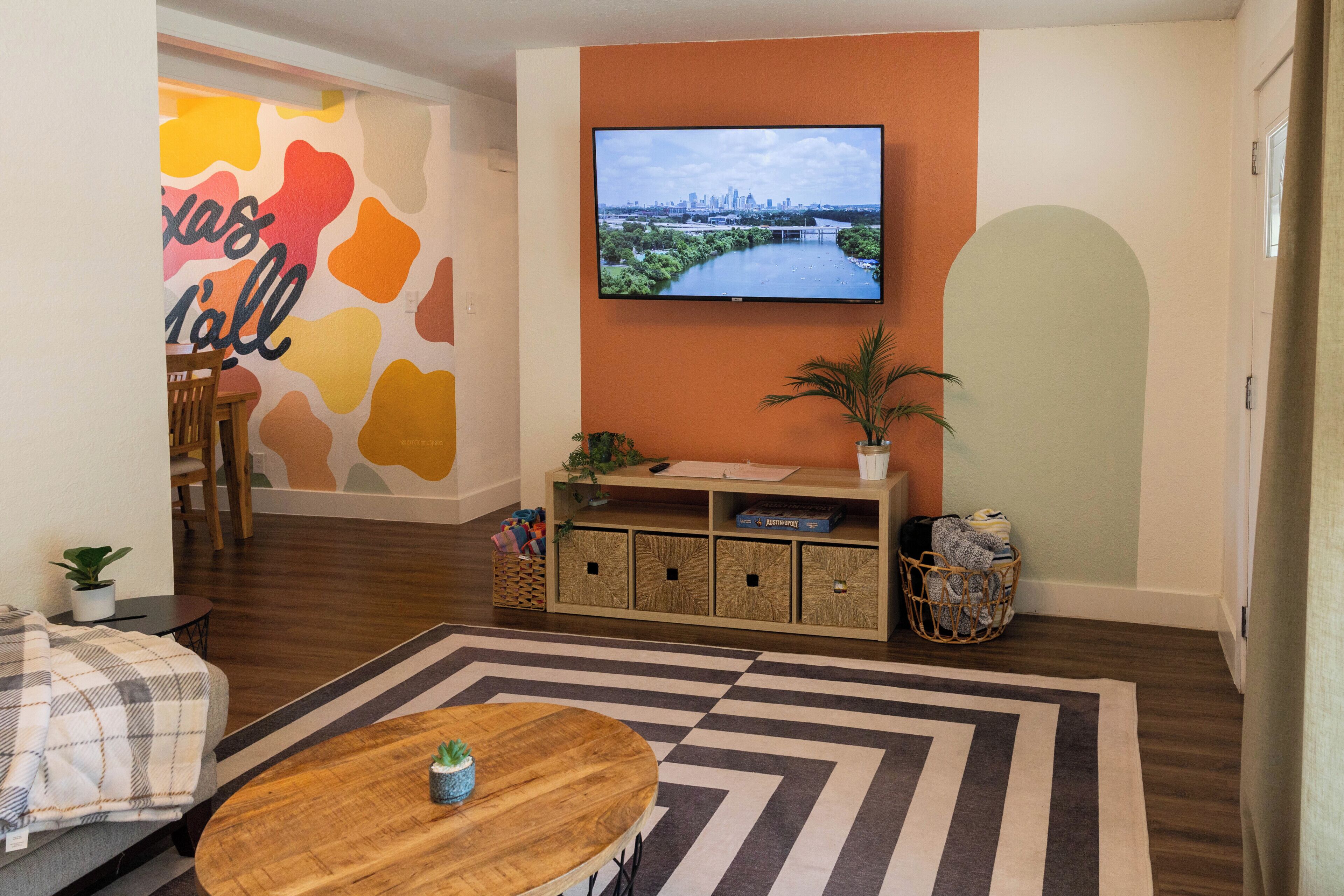 A living room with a television, a sofa, a coffee table, a patterned rug, and a wall with abstract art.