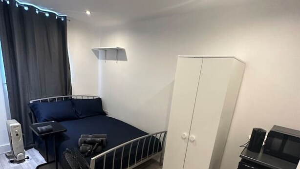 Un dormitorio con cama, armario, escritorio y ventilador.