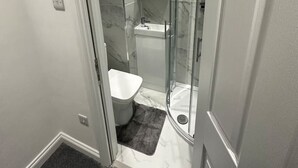 A bathroom with a glass shower enclosure, a toilet, and a sink.