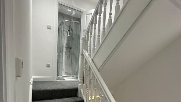 A staircase with dark carpeted steps and white balusters.