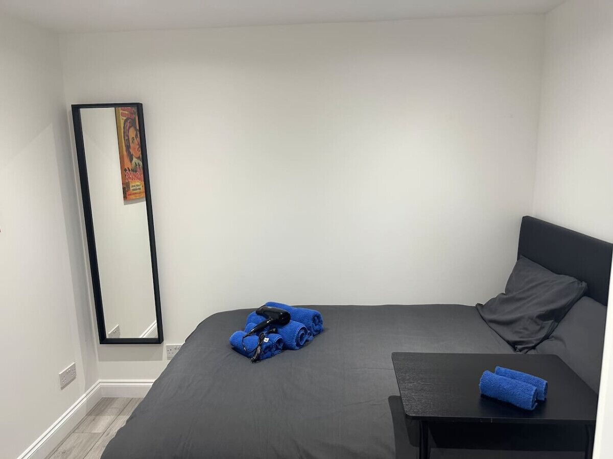 A bedroom with a bed, a bedside table, a mirror, and a towel.