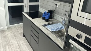 A modern kitchen with dark cabinets, a stainless steel sink, and a built-in oven.