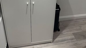 A large, light grey wardrobe with two doors and a handle on each.