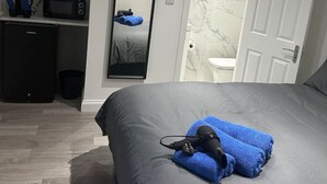 A bedroom with a large bed, a desk with a computer, a mirror, and a door leading to a bathroom. - Central London- Zone 1/2 En-suite Room (Greater London)