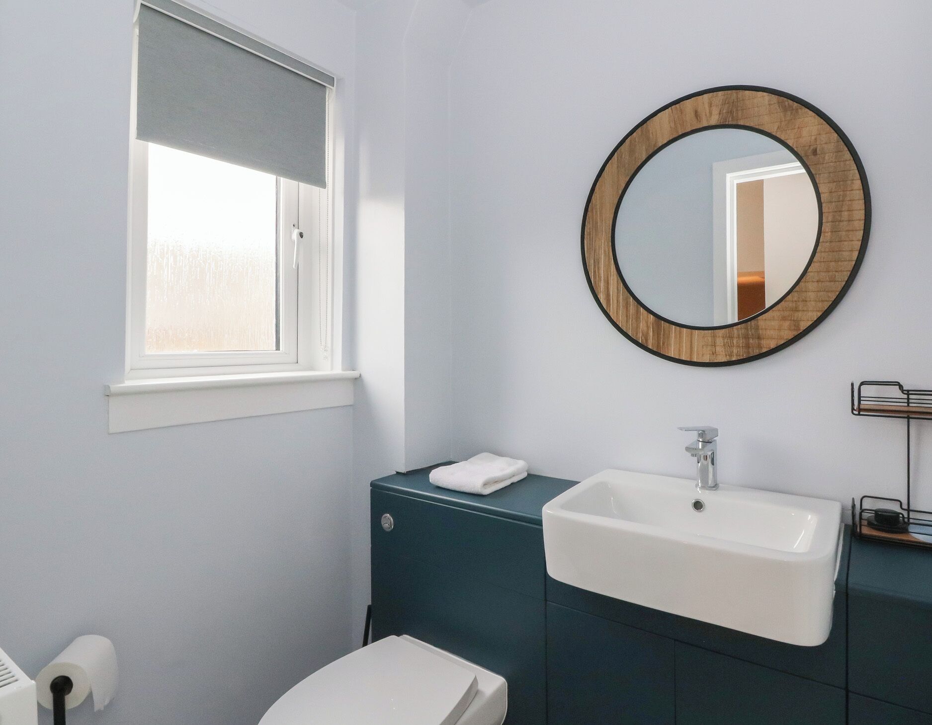 A bathroom with a toilet, a sink, a mirror, and a window.