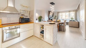 A modern kitchen with white cabinetry, a built-in oven, and a wooden countertop.