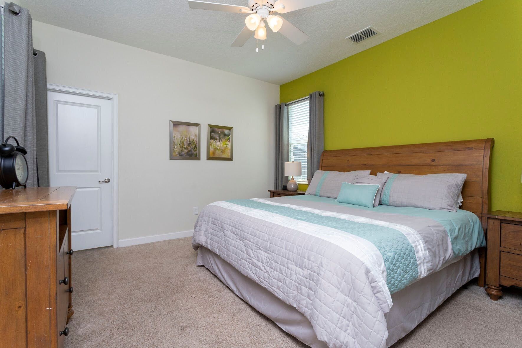A bedroom with a bed, a nightstand, a dresser, and a ceiling fan.