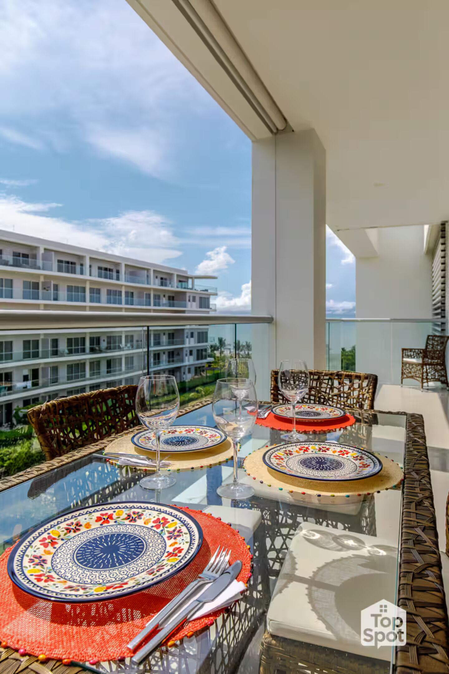 A dining area with glass tables and wicker chairs, overlooking a modern building.