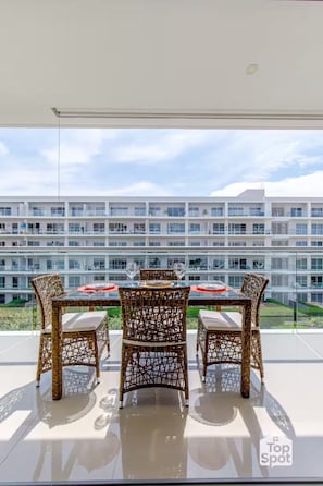 A balcony with wicker chairs and a table, overlooking a modern building with multiple floors and balconies. - ¡Oceanfront TopSpot® @ Cartagena´s Best Beach! (Cartagena de Indias)