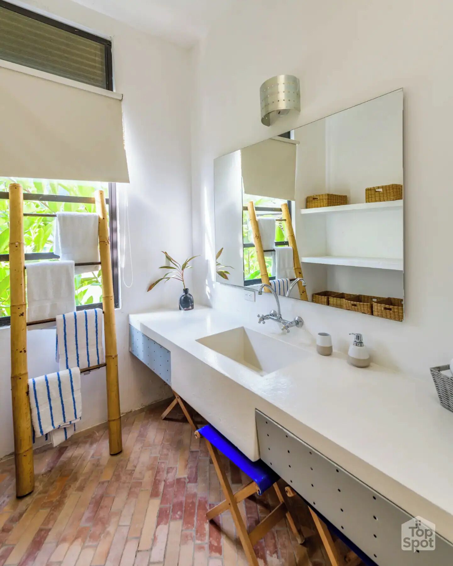 Une salle de bain moderne avec un grand lavabo blanc, un miroir et un porte-serviettes en bambou.
