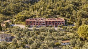 A multi-story building surrounded by dense forest, with a clear view of the surrounding landscape. - Mont&Lac | Lake View Apartment in Limone (Limone Sul Garda)
