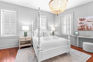 A bedroom with a four-poster bed, bedside tables, a chandelier, and artwork on the wall. - Rare, Historical Estate near Market St w. Parking (Charleston)