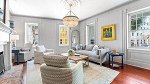 A spacious living room with a fireplace, a chandelier, and large windows. - Rare, Historical Estate near Market St w. Parking (Charleston)