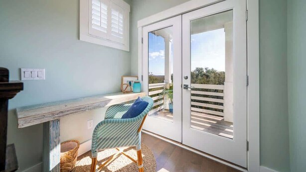 Un balcone con una sedia in vimini, un tavolino e vista sull'esterno.